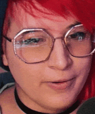 a woman with red hair wearing glasses and a choker .