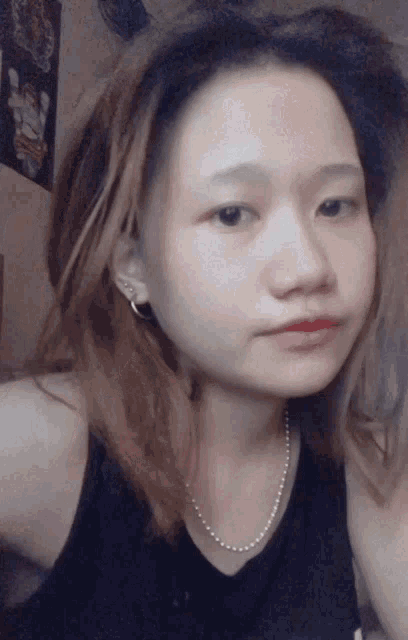 a girl wearing a pearl necklace and earrings looks at the camera