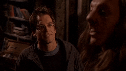 a man wearing glasses is smiling while talking to another man .