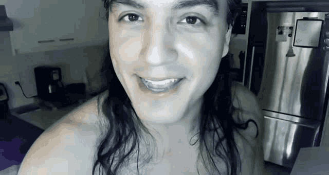 a man with long hair is smiling in a kitchen