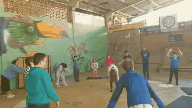 a group of children are doing yoga in front of a mural of a bird and a sign that says central