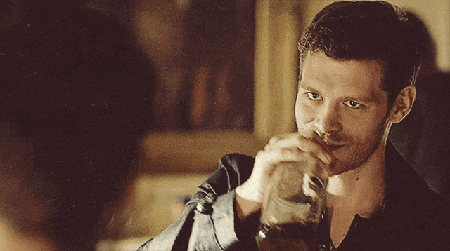 a man in a black jacket drinks from a bottle