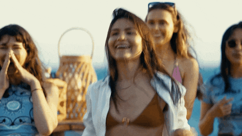 a woman in a bikini is laughing while standing next to another woman