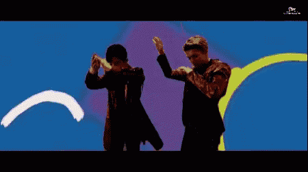 two men are dancing in front of a wall with the words come on shake it written on it