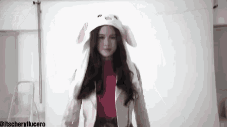 a woman is wearing a bunny hat and a pink turtleneck .
