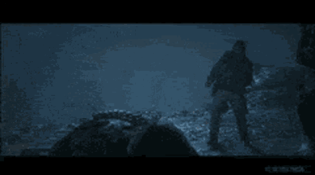 a man is laying on the ground while another man stands in the background .