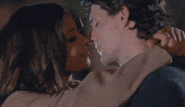 a man and woman are kissing in front of a building