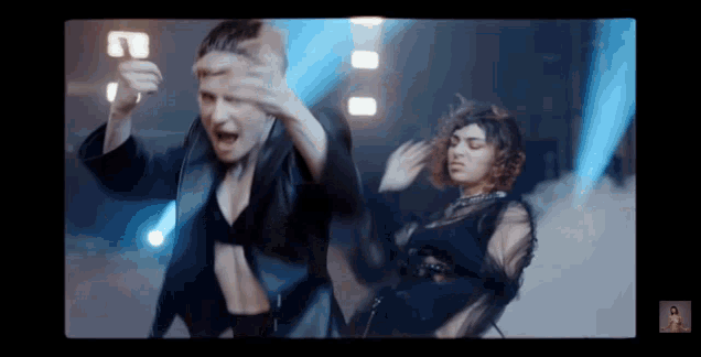 two women are dancing in front of a blue light .