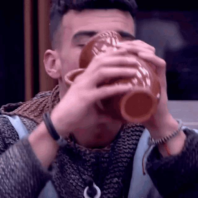 a man is drinking from a clay cup .