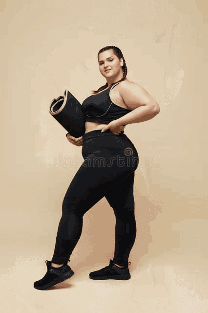 a plus size woman in a black bodysuit holds her hair