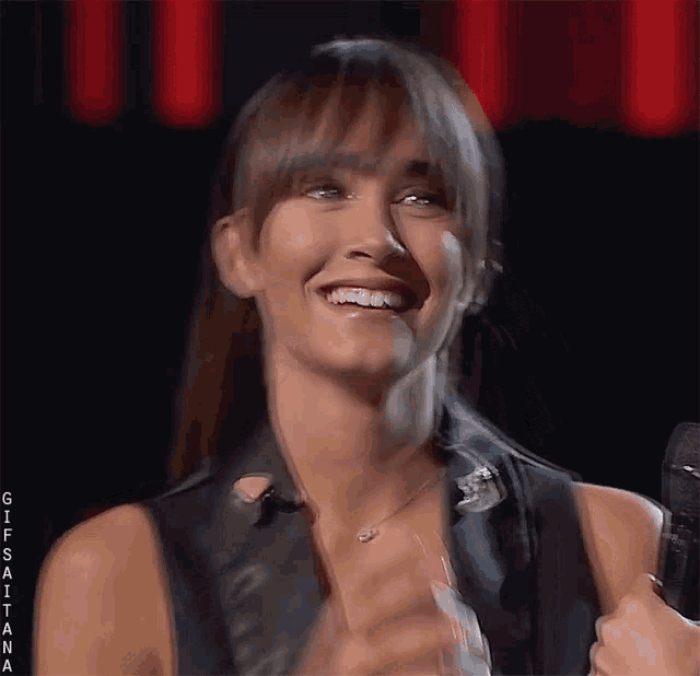 a woman is smiling while holding a microphone and wearing braces on her teeth .