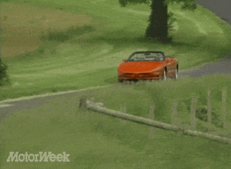 an orange sports car is driving down a dirt road with motorweek written on the bottom right