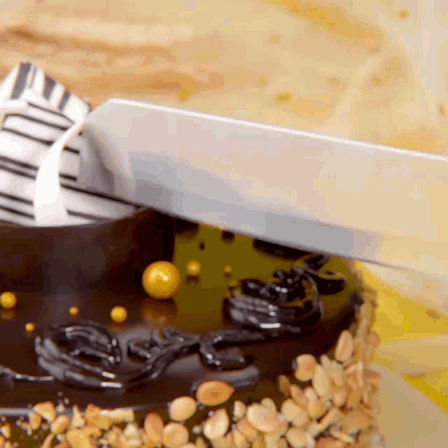 a knife is being used to cut a chocolate cake with peanuts