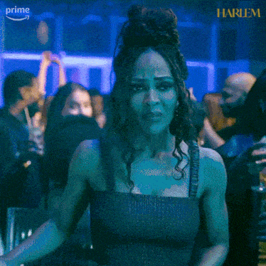a woman in a black dress is standing in front of a crowd with the word harlem on the bottom right corner