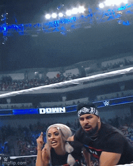 a man and a woman in a wrestling ring with a down sign behind them