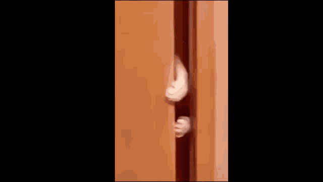 a black and white cat is peeking through a door