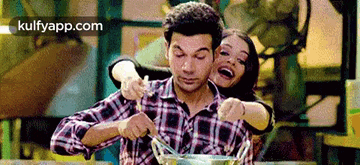 a woman is hugging a man while he holds a bowl of food