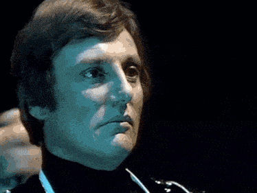 a close up of a man 's face with a turtleneck and a stethoscope around his neck .