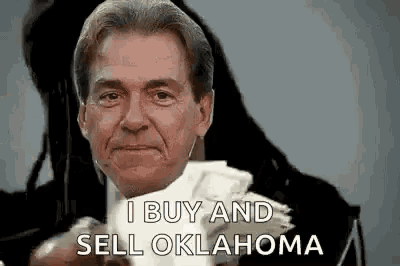 a man in a suit is holding a pile of money and says `` i buy and sell oklahoma '' .