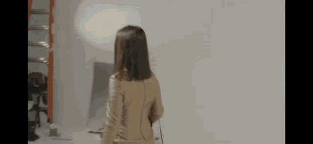 a woman is standing in front of a white wall in a studio holding a microphone .