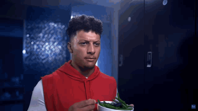 a man in a red sweatshirt is eating green beans