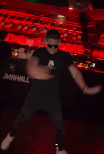 a blurry photo of a man wearing sunglasses and a black shirt that says ' a man ' on it