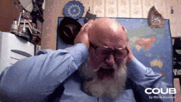 a man with glasses and a beard is covering his ears with his hands
