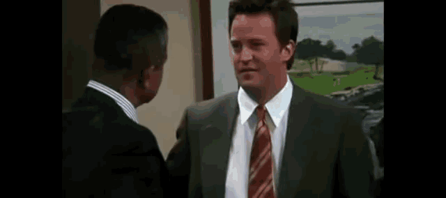 a man in a suit and tie is talking to another man in a suit .