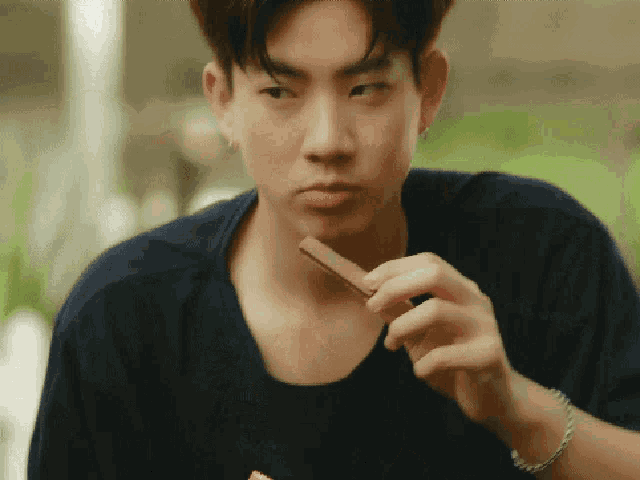 a young man is eating a piece of chocolate