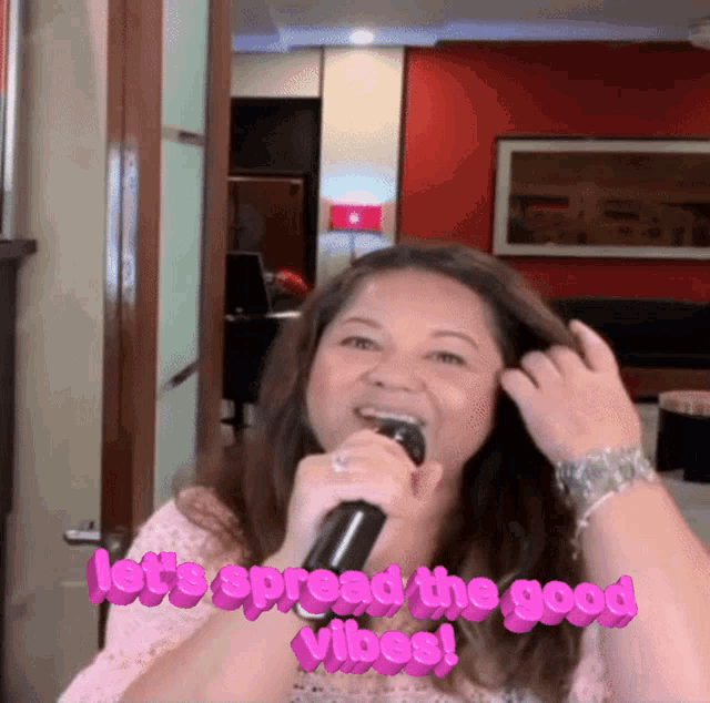 a woman singing into a microphone with the words " let 's spread the good vibes " above her