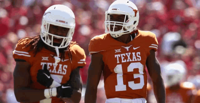 two texas football players wearing orange uniforms are standing next to each other