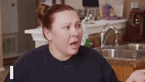 a woman is making a funny face in front of a sink .