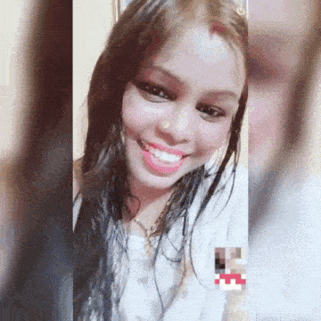 a woman is smiling and looking at the camera while wearing a nose ring .