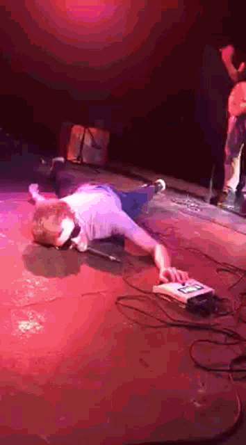 a man is laying on the floor on a stage while playing a keyboard