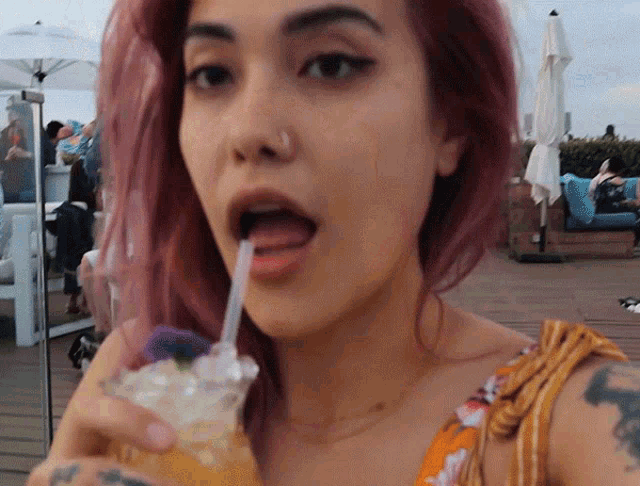 a woman with a nose ring drinking through a straw