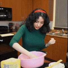 a woman is mixing something in a pink bowl