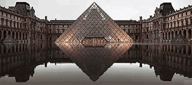 the pyramid of louvre is reflected in the water surrounding it .