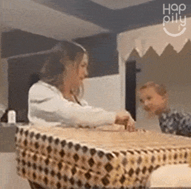 a woman and a child are sitting at a table with a table cloth that says hap pillu