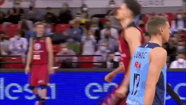 a basketball player wearing a number 12 jersey stands next to another player