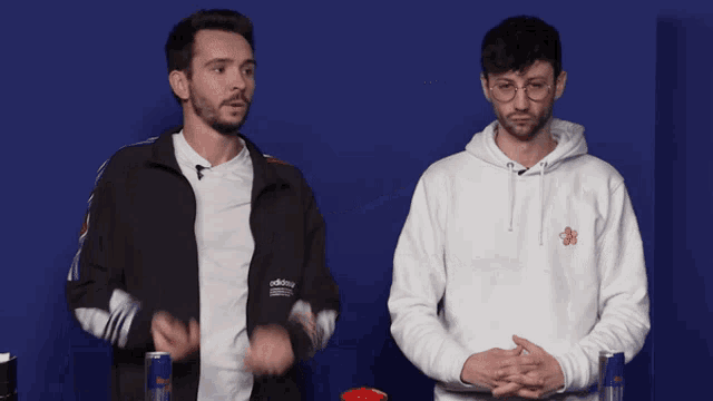 two men standing next to each other one wearing an adidas jacket