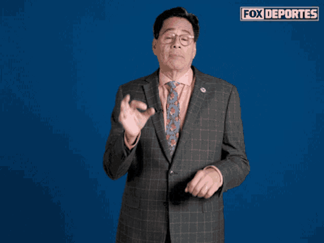 a man in a suit and tie stands in front of a blue background with fox deportes written on it