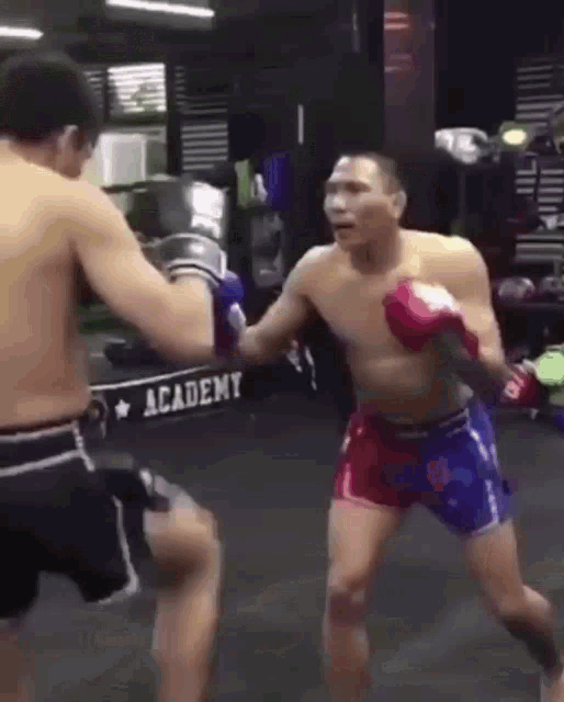 two men are boxing in a gym with a sign that says academy in the background