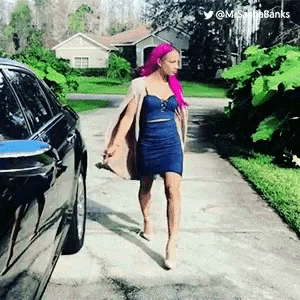 a woman with pink hair is walking down a street next to a car