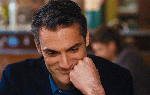 a man is smiling with his hand on his face