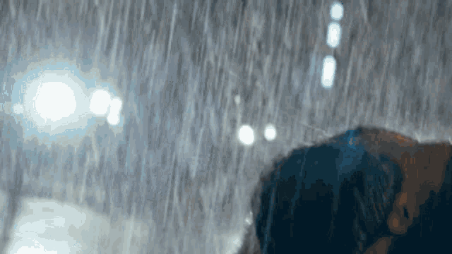 a couple is kissing in the rain at night .