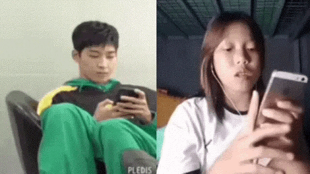 a man and a woman are sitting in a chair looking at their phones .