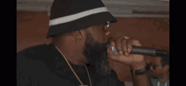 a man singing into a microphone while wearing a bucket hat