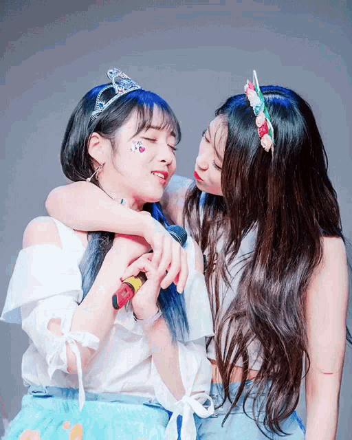 a girl with a crown on her head is kissing another girl on the cheek