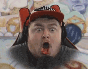 a man wearing a red hat and headphones is making a surprised face .
