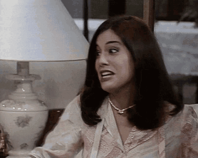 a woman sitting in front of a lamp with a white shade